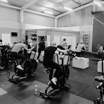 B&W Team Workout - Many ladies Using assault bikes and box jumps in the gym