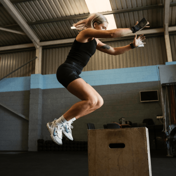 Anita pictured at a side angle doing box jumps in the gym